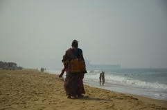 Indian woman street vendor walking on the beach stock photo Indian woman street vendor walking on the beach stock photo