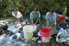 Indian women wash laundry in flowing stream