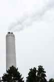 Industrial chimney with smoke with tree in the front stock image Industrial chimney with smoke with tree in the front stock image