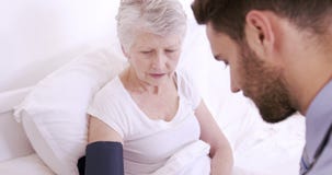 Infermiere maschio che misura pressione sanguinosa alla donna senior stock footage Infermiere maschio che misura pressione sanguinosa alla donna senior stock footage