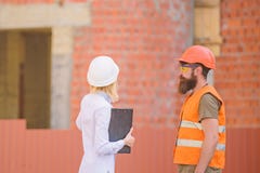 Ingeniero de la mujer y constructor brutal barbudo discutir progreso de la construcci?n Discuta el plan del progreso Sector de la imagen de archivo Ingeniero de la mujer y constructor brutal barbudo discutir progreso de la construcci?n Discuta el plan del progreso Sector de la imagen de archivo