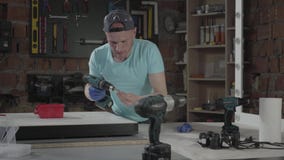 Ingeniero del amo del arte de la habilidad del retrato centrado en la perforaci?n de un agujero con la herramienta en el fondo de almacen de metraje de vídeo Ingeniero del amo del arte de la habilidad del retrato centrado en la perforaci?n de un agujero con la herramienta en el fondo de almacen de metraje de vídeo