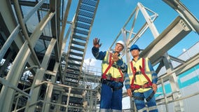 Ingenieur zwei, der ein neues Projekt mit großem Industriehintergrund bespricht stock footage Ingenieur zwei, der ein neues Projekt mit großem Industriehintergrund bespricht stock footage