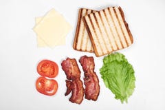 Ingredienti per produrre panino ortaggi freschi, pomodori, pane, becon, formaggio Isolato su fondo bianco, cima fotografia stock libera da diritti Ingredienti per produrre panino ortaggi freschi, pomodori, pane, becon, formaggio Isolato su fondo bianco, cima fotografia stock libera da diritti