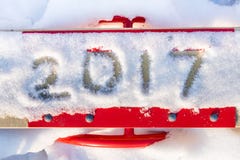 Inschrijving 2017 door sneeuw op de schommeling van de rode kinderen Stock Afbeeldingen Inschrijving 2017 door sneeuw op de schommeling van de rode kinderen Stock Afbeeldingen