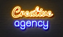 Insegna al neon creativa dell'agenzia sul fondo del muro di mattoni immagine stock Insegna al neon creativa dell'agenzia sul fondo del muro di mattoni immagine stock