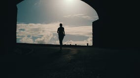 Inseguimento del colpo di una siluetta della donna che si esaurisce dal tunnel verso la luce solare Scoppio di luce intensa Alzan archivi video Inseguimento del colpo di una siluetta della donna che si esaurisce dal tunnel verso la luce solare Scoppio di luce intensa Alzan archivi video
