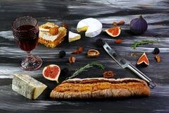 Insieme dello spuntino e del vino Baguette, bicchiere di vino, fichi, uva, dadi, varietà su un fondo nero, disposizione piana, sp immagini stock libere da diritti Insieme dello spuntino e del vino Baguette, bicchiere di vino, fichi, uva, dadi, varietà su un fondo nero, disposizione piana, sp immagini stock libere da diritti