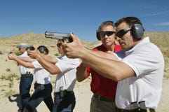 Instructor Assisting Officers With Hand Guns At Firing Range