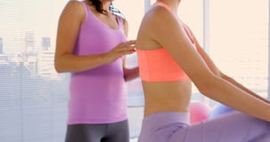Instructor de la aptitud que explica un ejercicio que estira a su cliente almacen de video Instructor de la aptitud que explica un ejercicio que estira a su cliente almacen de video