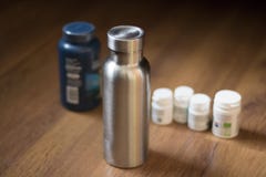 Insulated Stainless Bottle next to pill bottles stock photos Insulated Stainless Bottle next to pill bottles stock photos