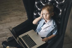 Intelligenter kleiner Kleinkindjunge mit großen Gläsern Kaffee bei der Anwendung ihres Laptops trinkend lizenzfreies stockfoto Intelligenter kleiner Kleinkindjunge mit großen Gläsern Kaffee bei der Anwendung ihres Laptops trinkend lizenzfreies stockfoto