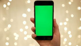 Intelligentes Telefon des Frauenhandgriffs auf Zusammenfassung verwischte bokeh des hellen Hintergrundhintergrundes Grüner Schirm stock video footage Intelligentes Telefon des Frauenhandgriffs auf Zusammenfassung verwischte bokeh des hellen Hintergrundhintergrundes Grüner Schirm stock video footage