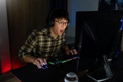 Involved Asian Man Cyber Sport Gamer Concentrated Playing Video Games On Computer At Night Dark Room At Home, ESport And Stock Photo