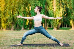 Ioga praticando da jovem mulher magro na natureza Pose de Virabhadrasana imagens de stock royalty free Ioga praticando da jovem mulher magro na natureza Pose de Virabhadrasana imagens de stock royalty free