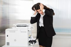 Irritated Businesswoman Looking At Paper Stuck In Printer royalty free stock photo Irritated Businesswoman Looking At Paper Stuck In Printer royalty free stock photo