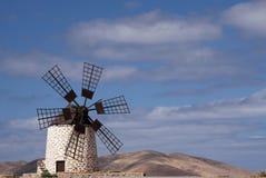 Isolated traditional windmill Molino de Tefia near La Olivia in dry arid hilly landscape against blue sky with cumulus clouds, royalty free stock photo Isolated traditional windmill Molino de Tefia near La Olivia in dry arid hilly landscape against blue sky with cumulus clouds, royalty free stock photo