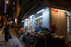 ISTANBUL, DIE TÜRKEI - 28. DEZEMBER 2015: Lebensmittelladen auf einer typischen Straße von Galata am Abend, eine verschleierte Fr stockfotografie ISTANBUL, DIE TÜRKEI - 28. DEZEMBER 2015: Lebensmittelladen auf einer typischen Straße von Galata am Abend, eine verschleierte Fr stockfotografie