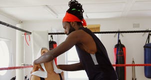 Istruttore che dà massaggio al pugile femminile in ring 4k video d archivio Istruttore che dà massaggio al pugile femminile in ring 4k video d archivio