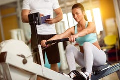 Istruttore che prende le note della donna sportiva in palestra fotografie stock Istruttore che prende le note della donna sportiva in palestra fotografie stock