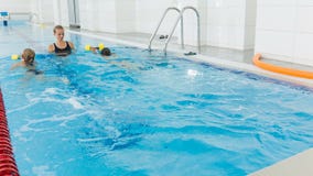 Istruttore e bambino che fanno gli esercizi nella piscina La vettura insegna alle ragazze a nuotare video d archivio Istruttore e bambino che fanno gli esercizi nella piscina La vettura insegna alle ragazze a nuotare video d archivio