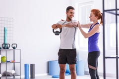 Istruttore e sportiva personali sorridenti che risolvono con il peso alla palestra fotografia stock Istruttore e sportiva personali sorridenti che risolvono con il peso alla palestra fotografia stock