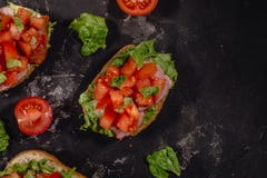 Italiano tradicional Bruschetta com tomates, molho da mussarela, as folhas da salada e o presunto desbastados em um fundo escuro foto de stock royalty free Italiano tradicional Bruschetta com tomates, molho da mussarela, as folhas da salada e o presunto desbastados em um fundo escuro foto de stock royalty free