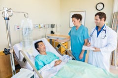 IV Bag On Rod With Medical Team Looking At Patient stock photo IV Bag On Rod With Medical Team Looking At Patient stock photo