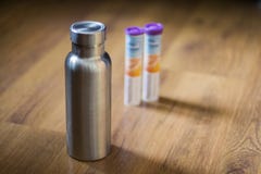 Izolująca Nierdzewna butelka obok rozerwalnych witamin pastylek obrazy stock Izolująca Nierdzewna butelka obok rozerwalnych witamin pastylek obrazy stock