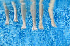 Jambes sous-marines drôles de famille dans la piscine, sous la vue de l'eau de la mère et des enfants, forme physique de vacances Images libres de droits Jambes sous-marines drôles de famille dans la piscine, sous la vue de l'eau de la mère et des enfants, forme physique de vacances Images libres de droits