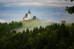 Jamnik church on a hillside in the spring, foggy weather at sunset in Slovenia, Europe. Mountain landscape shortly after spring ra Stock Images Jamnik church on a hillside in the spring, foggy weather at sunset in Slovenia, Europe. Mountain landscape shortly after spring ra Stock Images