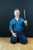Japansk sport för Caucasian manlig utbildning, iaido Sitta på golvet som rymmer ett japanskt svärd fotografering för bildbyråer Japansk sport för Caucasian manlig utbildning, iaido Sitta på golvet som rymmer ett japanskt svärd fotografering för bildbyråer