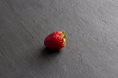 Jeden czerwona pi?kna truskawka w g?r? na czarnym zmroku betonu tle, minimalista Boczny widok, kopii przestrze? dla tw?j teksta M fotografia royalty free Jeden czerwona pi?kna truskawka w g?r? na czarnym zmroku betonu tle, minimalista Boczny widok, kopii przestrze? dla tw?j teksta M fotografia royalty free