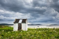 Jetez la maison dans le domaine de machair à côté de la plage sablonneuse, sous le ciel orageux foncé photos libres de droits Jetez la maison dans le domaine de machair à côté de la plage sablonneuse, sous le ciel orageux foncé photos libres de droits