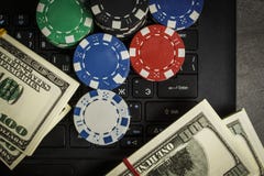 Jetons de poker et paquets de dollars sur un ordinateur portable images stock Jetons de poker et paquets de dollars sur un ordinateur portable images stock