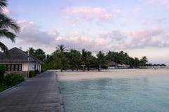 Jetée en bois sur une plage blanche de sable avec des palmiers et un coucher du soleil gentil avec un ciel avec des nuages photo libre de droits Jetée en bois sur une plage blanche de sable avec des palmiers et un coucher du soleil gentil avec un ciel avec des nuages photo libre de droits