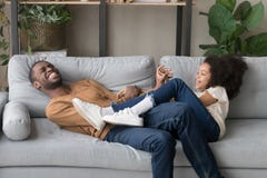 Jeu drôle riant de père avec la fille se trouvant sur le sofa photo libre de droits Jeu drôle riant de père avec la fille se trouvant sur le sofa photo libre de droits