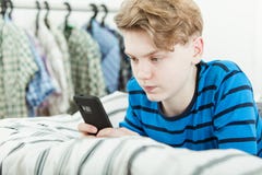 Jeune adolescent textotant un message sur un mobile photographie stock Jeune adolescent textotant un message sur un mobile photographie stock