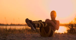 Jeune bel athlète de femme pratiquant sur la plage faisant des exercices pour les muscles de l'ABS au coucher du soleil Vrillage clips vidéos Jeune bel athlète de femme pratiquant sur la plage faisant des exercices pour les muscles de l'ABS au coucher du soleil Vrillage clips vidéos
