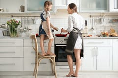 Jeune bonne d'enfants avec la petite fille mignonne faisant cuire ensemble photo stock Jeune bonne d'enfants avec la petite fille mignonne faisant cuire ensemble photo stock