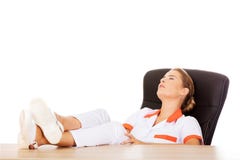 Jeune docteur féminin fatigué dormant avec des jambes sur le bureau Images libres de droits Jeune docteur féminin fatigué dormant avec des jambes sur le bureau Images libres de droits