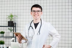 Jeune docteur masculin beau de sourire utilisant la tablette Technologies dans le concept de médecine photos stock Jeune docteur masculin beau de sourire utilisant la tablette Technologies dans le concept de médecine photos stock