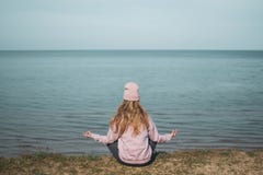 Jeune femme adulte dans le chapeau rose seul se reposant sur les bluffs, regard de la mer, concept de libert?, l'atmosph?re paisi image stock Jeune femme adulte dans le chapeau rose seul se reposant sur les bluffs, regard de la mer, concept de libert?, l'atmosph?re paisi image stock