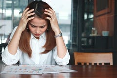 Jeune femme asiatique soumise à une contrainte frustrante d'affaires analysant des écritures ou des diagrammes dans le lieu de tr photographie stock Jeune femme asiatique soumise à une contrainte frustrante d'affaires analysant des écritures ou des diagrammes dans le lieu de tr photographie stock