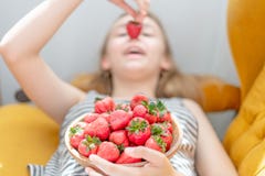 Jeune femme attirante s'?tendant sur le sofa dans un salon ? la maison de chambre familiale, mangeant la fraise fra?che photographie stock libre de droits Jeune femme attirante s'?tendant sur le sofa dans un salon ? la maison de chambre familiale, mangeant la fraise fra?che photographie stock libre de droits