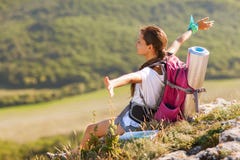 Jeune femme avec le sac à dos se reposant sur le bord de la falaise image libre de droits Jeune femme avec le sac à dos se reposant sur le bord de la falaise image libre de droits