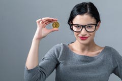 Jeune femme avec une pièce de monnaie de bitcoin d'or photo stock Jeune femme avec une pièce de monnaie de bitcoin d'or photo stock