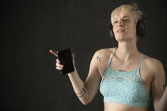 Jeune femme blonde dans la danse bleue de camisole avec des écouteurs dessus photographie stock Jeune femme blonde dans la danse bleue de camisole avec des écouteurs dessus photographie stock
