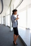 Jeune femme d'affaires Standing In Corridor de café potable moderne d'immeuble de bureaux image libre de droits Jeune femme d'affaires Standing In Corridor de café potable moderne d'immeuble de bureaux image libre de droits