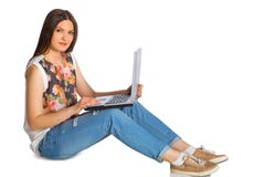 Jeune femme dans des jeans avec l'ordinateur portable se reposant sur le plancher photographie stock libre de droits Jeune femme dans des jeans avec l'ordinateur portable se reposant sur le plancher photographie stock libre de droits
